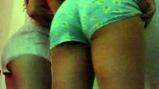 Two lesbians kiss passionately while shaking their asses seductively for the camera.