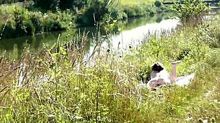 Naked mature woman sunbathes on wild beach while watched
